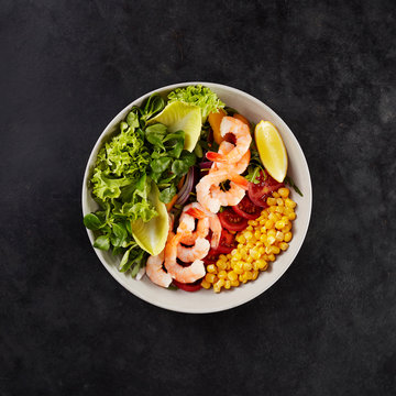 Bowl with fresh corn, tomatoes, lemon, shrimps, chicory and lollo bionda lettuce