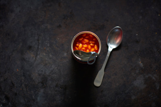 Spoon and can of beans in tomato sauce