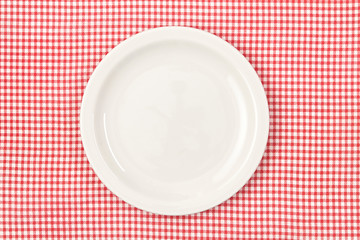 White empty plate on red checked tablecloth