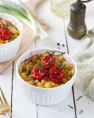 Casserole in portions of the molds with the tomato on the table.