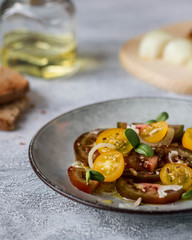 Yellow and black tomato salad on a grey plate, side view.