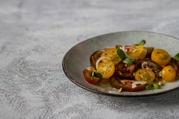 Salad of yellow and black tomatoes on a gray plate, photo with free space.