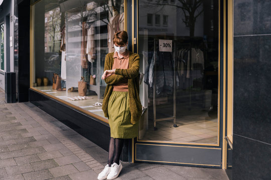 Woman wearing mask standing in front of her closed clothing store
