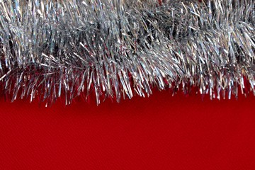 Silver Christmas decorations on a red background. White tinsel for christmas tree. Gray rain isolated on red.