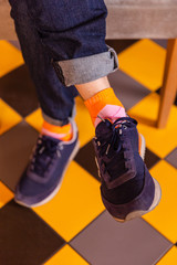 man feets in sneakers. stylish mens footwear. blue sneakers and orange socks