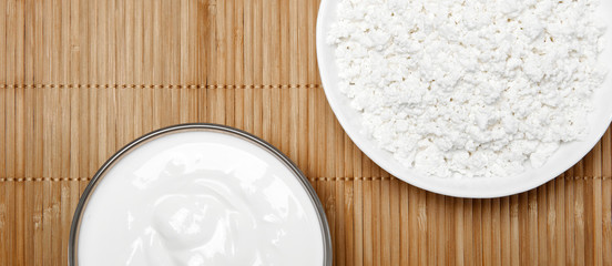 still life background with fragments of bowls with cottage cheese and sour cream on the table, top view