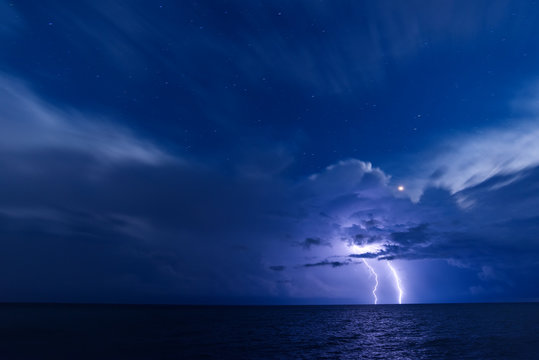 Two lightning bolts over the sea with starry sky background