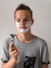 Cute handsome young man, teenager shaves first time, concept