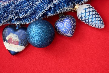 Set of blue Christmas tree decorations. Four blue christmas tree toys on red background with place for text. Glass toy heart. Shiny ball. Glass fir cone. Blue christmas decorations