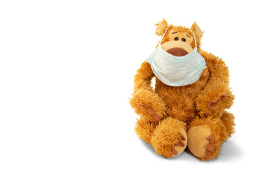 Stuffed animal in a face mask. Toy teddy bear isolated in a face medical mask on his mouth, banner fo site.
