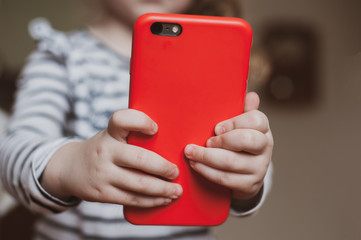 Cute girl holding a red mobile phone in her hands