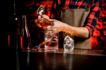 close-up bartender pouring liquor into glassy mixing cup