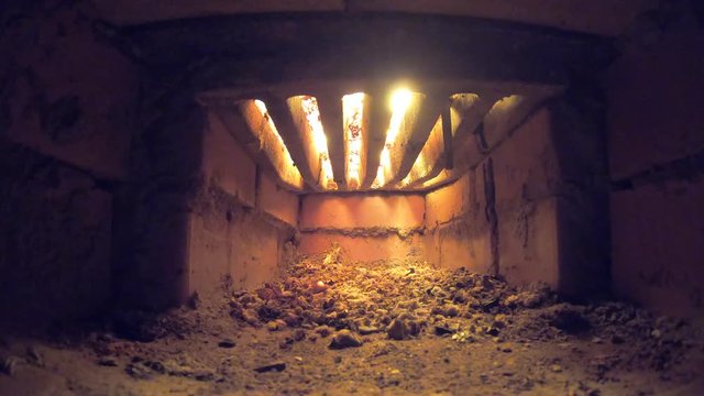 A flame of fire burns on a grate in a large oven. Crematorium