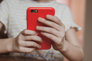 Cute girl holding a red mobile phone in her hands