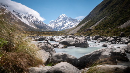 Fototapeta na wymiar Panoramic long shutter speed shot of alpine valley with impressive peak on its end (Mt Cook) with glacial river used as leading line. Shot in Aoraki / Mt Cook National Park, New Zealand