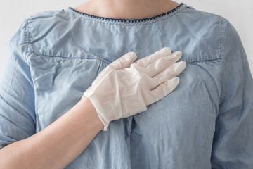 Close-up woman doctor hands in white medical rubber gloves on heart blue coat background. Disinfection, health, care, safety concept. Stop virus and coronovirus