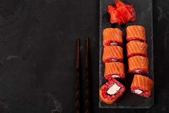 tasty sushi rolls on a gray background with traditional chopsticks and fish