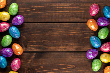 Minimal easter concept with colored easter eggs as a frame. Wooden background with copy space, top view