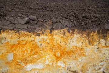 The side of a freshly dug field drainage ditch showing soil stratification humic topsoil and iron...