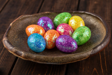 colored easter eggs on a clay plate. holiday concept with red, yellow, green, blue colors. wooden background