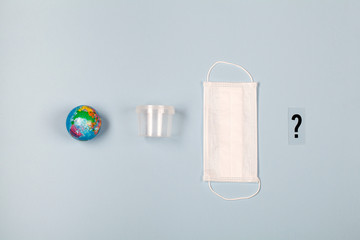 Earth, plastic disposable box, medical mask and question mark on blue background.