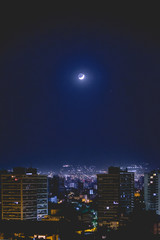Crescent moon over Santiago skyline with blue sky night, Chile
