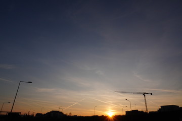 amazing sky at sunset with small clouds and a trace of the plane or contrail in the city against the background of houses and the Church. the sun's rays are visible through the clouds.