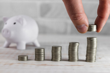 Hand of investor putting silver coins on money towers. Concept of finance and growing saving wealth