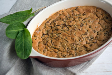 Sweet homemade sorrel pie and green Rumex leaves on a white wooden background. Original simple sweet pastries. Dessert.