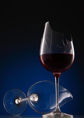 Fototapeta na wymiar broken wine glasses with wine on a dark blue background