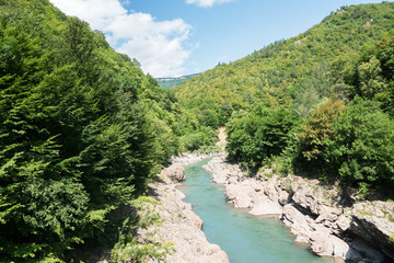 Fototapeta na wymiar picturesque view of blue river surrounded by rocks in beautiful green mountains, summer, blue sky, traveling in scenic places 