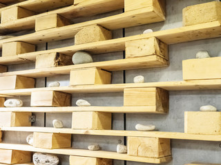 Decorative wooden shelves with pebbles of various sizes hanging on a gray concrete wall