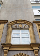 A modern window with decorative elements on the grey facade of the building