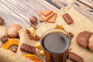 A faceted glass of tea in a vintage Cup holder, bagels, chocolate cakes, cookies and chocolate on a background of rough homespun fabric. Close up.