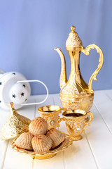 Ramadan concept. Maamoul traditional arab filled pastry or cookie with dates or nuts served with coffee golden set. Eastern sweets. Close up. White wooden background.