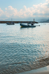 a fragment of a sandy beach with a moving sea wave with small motor boats parked in a quiet bay in the Greek resort of Hersonissos