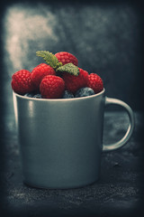 Cup with raspberries and blueberries with mint leaves
