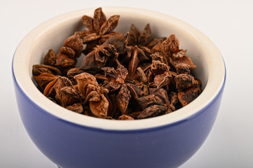 star anise in a blue ceramic spice mortar on a white background. Close up.