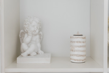 Beautiful cute figure of an angel on a white shelf