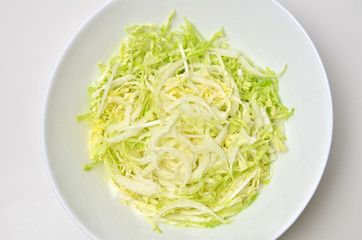 Fresh chinese cabbage salad in bowl on white table background. Vegan food lifestyle. Top view.