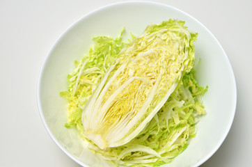 Half a head of chinese cabbage in white bowl over white table. Vegan food lifestyle concept. Top view.