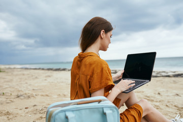 Woman tourist sitting on the beach or relaxing laptop