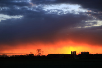 Kolorowy zachód słońca nad obszarem wiejskim, złote i burzowe chmury.