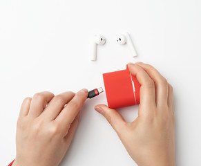 two female hands are holding a cable and a red box with wireless headphones