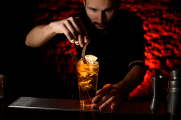 male bartender neatly decorates glass with negroni cocktail by leaf