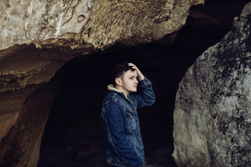 Young man in the mountains in a cave