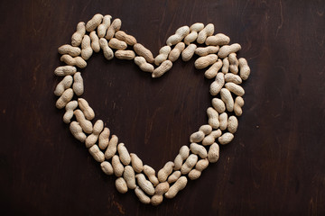 Heart shaped peanuts on a brown wooden table