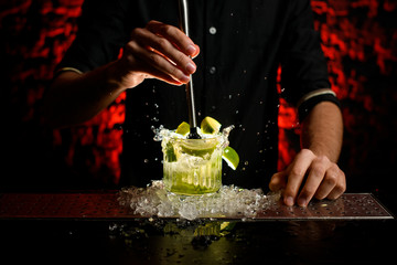 close-up barman in black t-shirt mix cocktail using metal madler