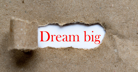 Dream big - red colour phrase on brown torn paper. Business, inspiration content.