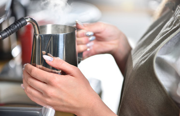 Young girl barista makes coffee on a large professional coffee machine, hands closeup. The concept of a small business and work for a student.